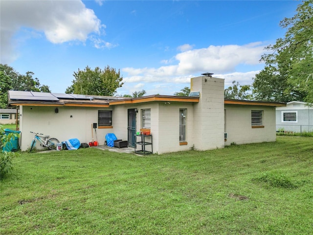 back of property featuring a yard and solar panels