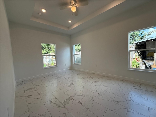 empty room featuring a tray ceiling and ceiling fan