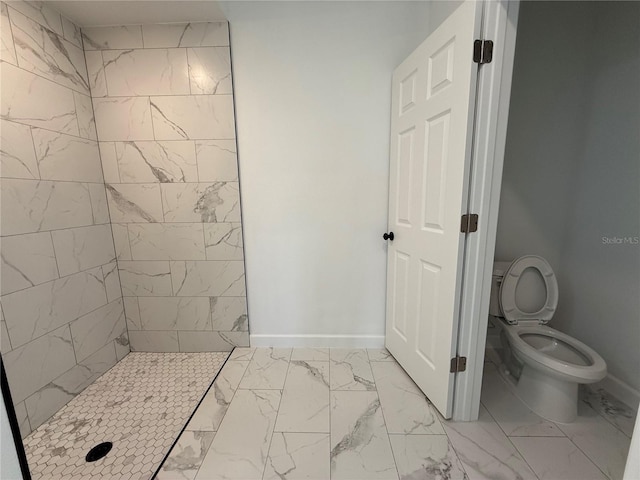 bathroom featuring a tile shower and toilet