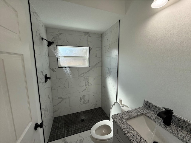 bathroom with vanity, toilet, and tiled shower