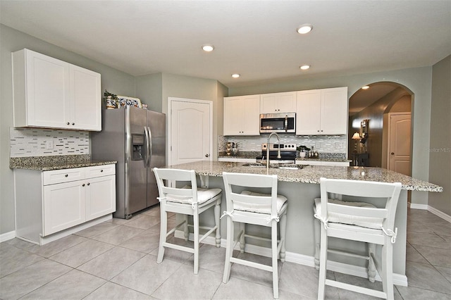 kitchen featuring white cabinetry, stainless steel appliances, a kitchen island with sink, and sink