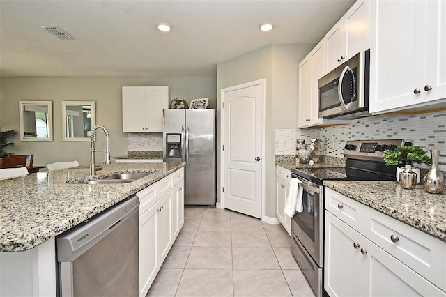 kitchen with appliances with stainless steel finishes, white cabinetry, sink, a kitchen island with sink, and light tile patterned floors