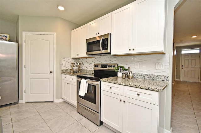 kitchen with appliances with stainless steel finishes, white cabinetry, light stone counters, tasteful backsplash, and light tile patterned flooring