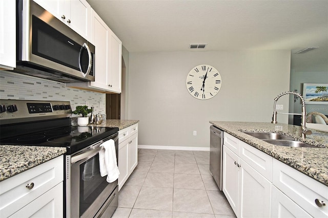 kitchen featuring appliances with stainless steel finishes, sink, white cabinets, and light stone counters