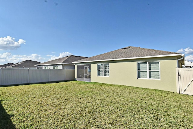 rear view of property featuring a sunroom and a lawn