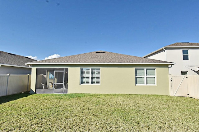 back of property with a sunroom and a lawn