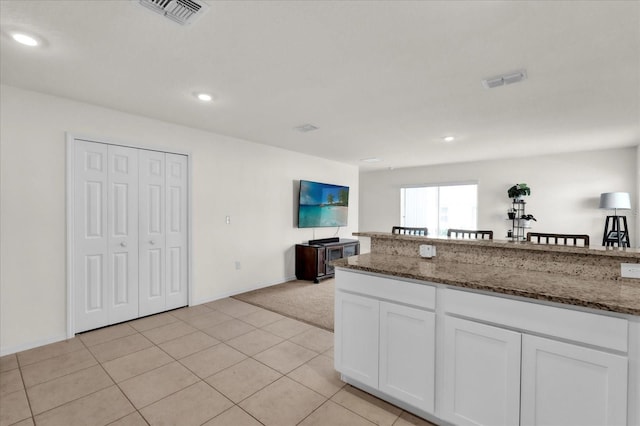 kitchen with dark stone counters, open floor plan, white cabinetry, and visible vents