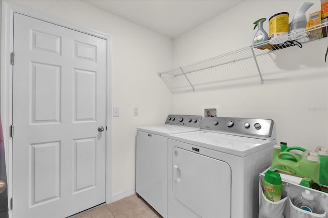 laundry area featuring light tile patterned floors, laundry area, washing machine and dryer, and baseboards