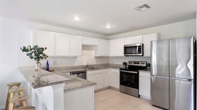 545 Jerry Ln, Haines City, FL 33844 - kitchen with appliances with stainless steel finishes, a peninsula, light stone countertops, white cabinetry, and recessed lighting