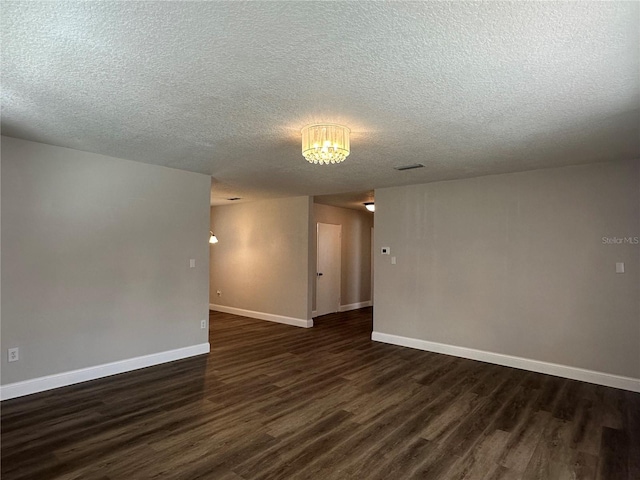 unfurnished room with dark wood-type flooring and a textured ceiling