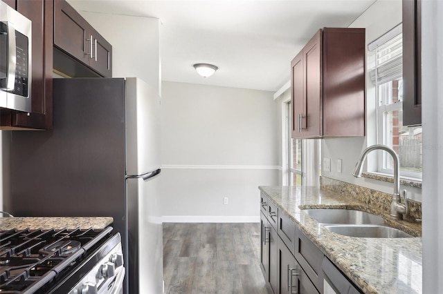 kitchen with hardwood / wood-style floors, stainless steel appliances, sink, and light stone countertops