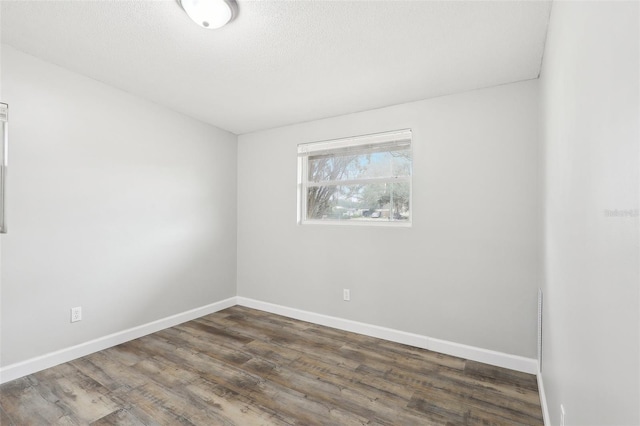 empty room with dark wood-type flooring and a textured ceiling