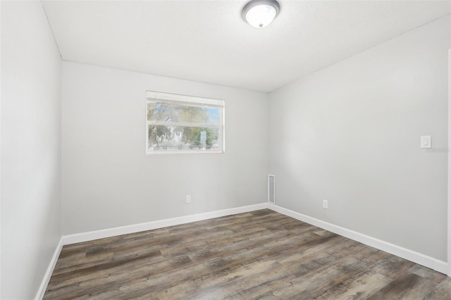 spare room with a textured ceiling and dark hardwood / wood-style floors