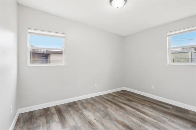 unfurnished room featuring a healthy amount of sunlight and dark wood-type flooring