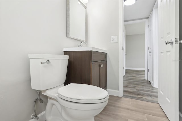 bathroom with toilet, hardwood / wood-style flooring, and vanity