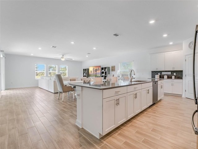 kitchen featuring sink, light hardwood / wood-style floors, white cabinets, and a center island with sink