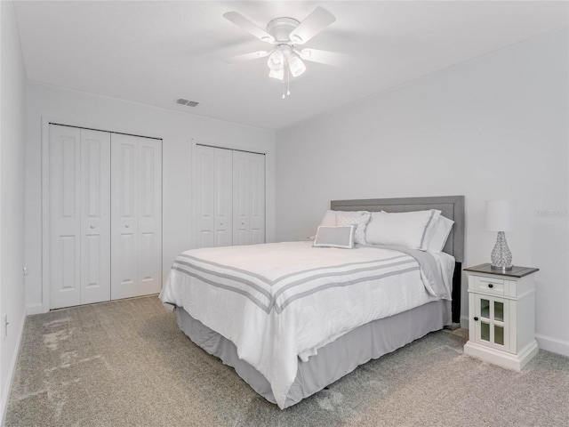 bedroom with two closets, carpet floors, and ceiling fan