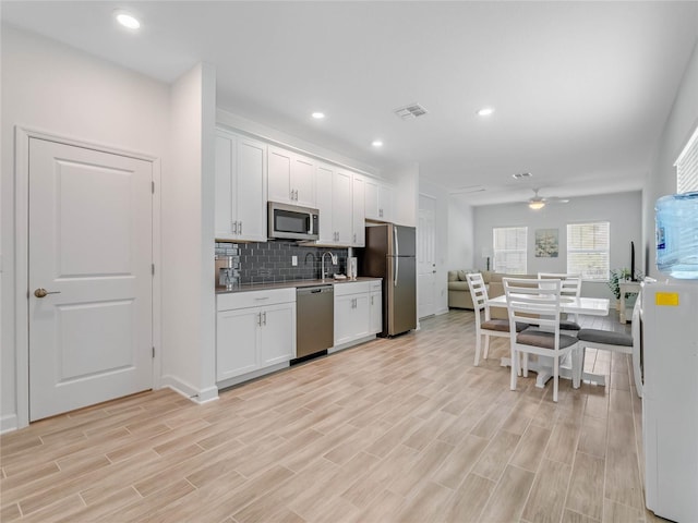 kitchen featuring backsplash, light hardwood / wood-style flooring, stainless steel appliances, and white cabinets