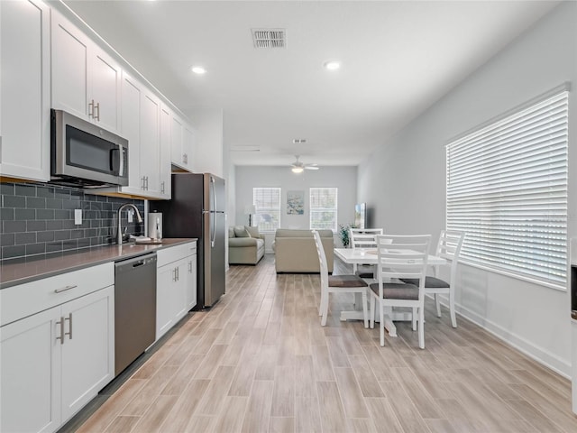 kitchen with tasteful backsplash, sink, white cabinets, and appliances with stainless steel finishes