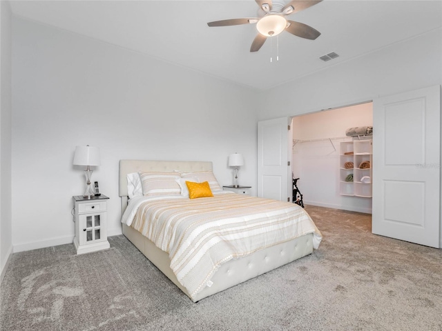 bedroom with a spacious closet, ceiling fan, and carpet