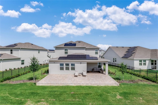 back of house featuring an outdoor living space, a yard, a patio, and solar panels