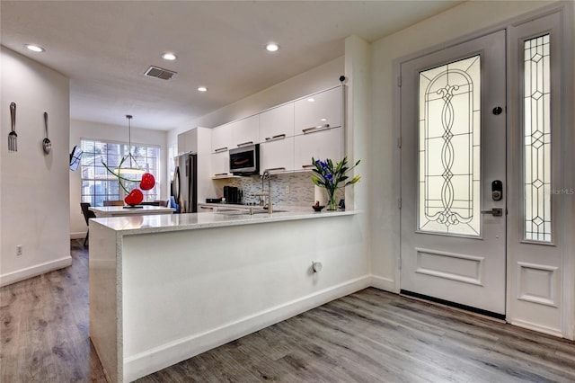 kitchen featuring white cabinetry, appliances with stainless steel finishes, pendant lighting, and kitchen peninsula