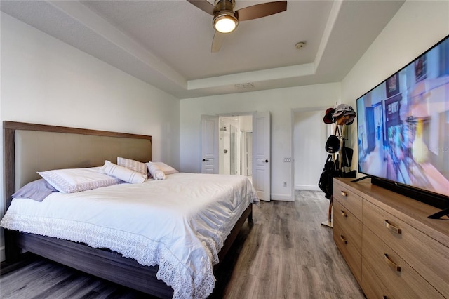 bedroom featuring ceiling fan, a tray ceiling, and hardwood / wood-style floors