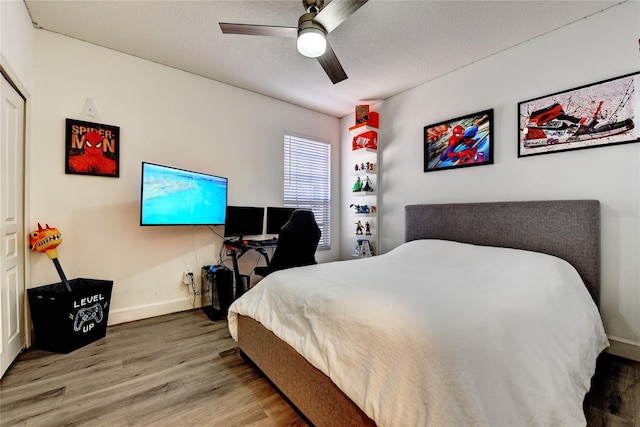 bedroom featuring ceiling fan, hardwood / wood-style floors, and a textured ceiling