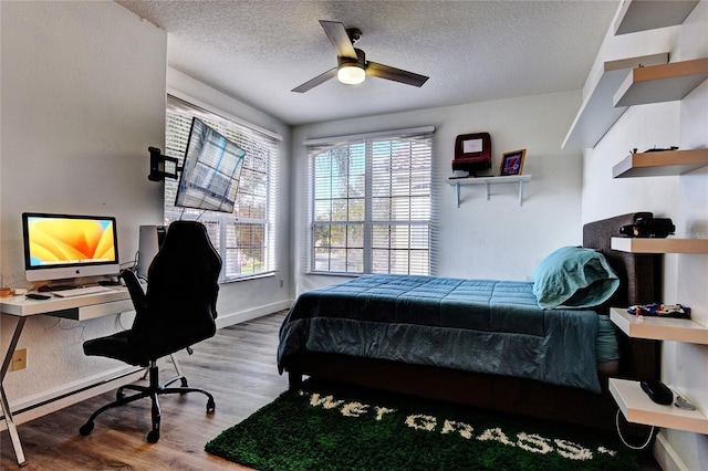 bedroom featuring hardwood / wood-style flooring, ceiling fan, and a textured ceiling