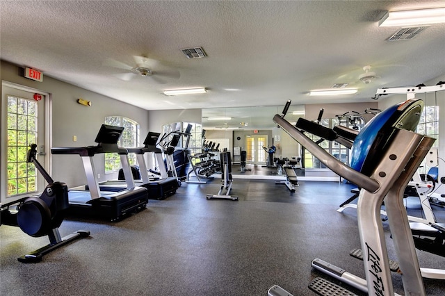 exercise room with ceiling fan and a textured ceiling