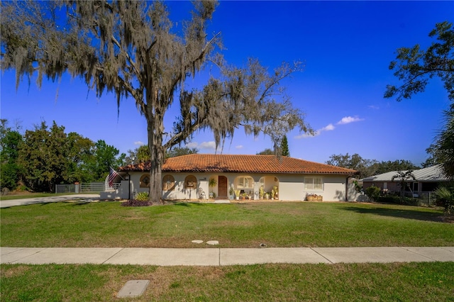 mediterranean / spanish-style home with a tile roof, a front lawn, and stucco siding