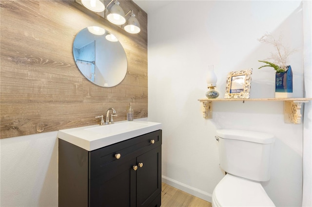 bathroom featuring vanity, hardwood / wood-style flooring, wooden walls, and toilet