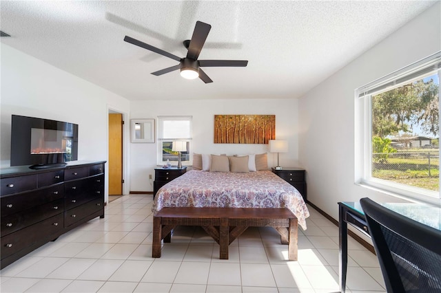 tiled bedroom with multiple windows, ceiling fan, and a textured ceiling