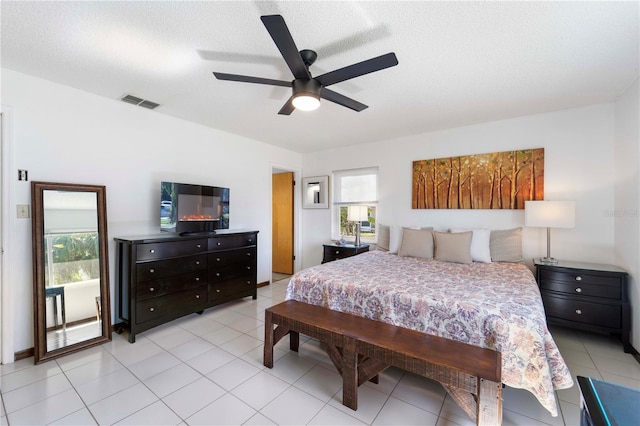 tiled bedroom with ceiling fan and a textured ceiling