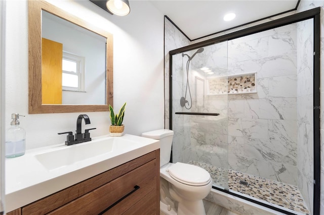 bathroom featuring vanity, a shower with door, and toilet