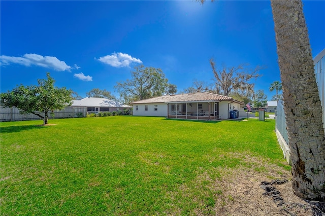 rear view of property with a lawn and a sunroom