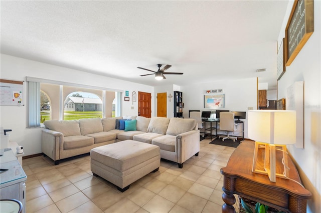 tiled living room with ceiling fan and a textured ceiling