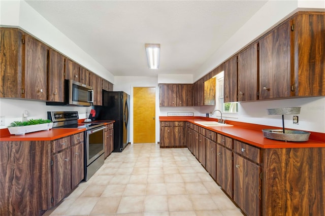 kitchen featuring stainless steel appliances, sink, a textured ceiling, and dark brown cabinetry