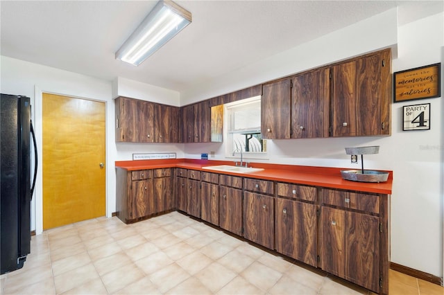 kitchen with black fridge, sink, and dark brown cabinets