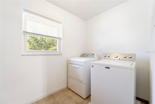 clothes washing area featuring light tile patterned flooring and washer and clothes dryer