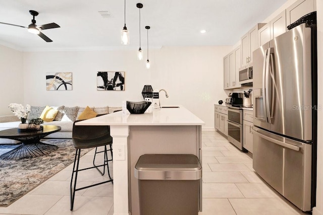 kitchen with sink, a kitchen breakfast bar, hanging light fixtures, stainless steel appliances, and a center island with sink