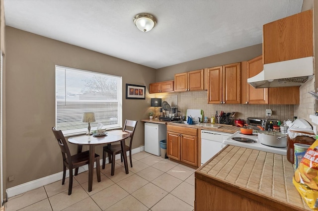 kitchen with light tile patterned floors, backsplash, and white dishwasher