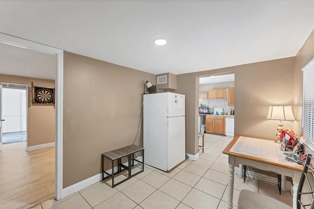 kitchen with white appliances, light brown cabinets, and light tile patterned flooring