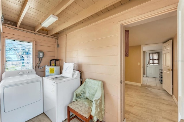 clothes washing area featuring light wood-type flooring, wooden ceiling, wooden walls, washer and clothes dryer, and water heater