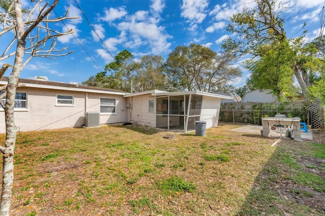 rear view of house with a sunroom, central AC unit, a patio area, and a lawn