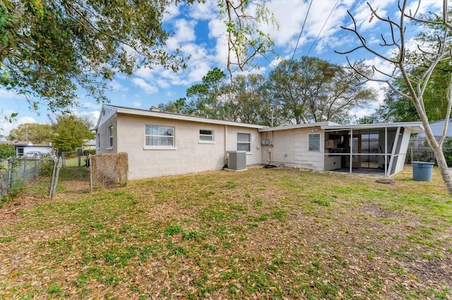 back of property with a yard, central AC unit, and a sunroom