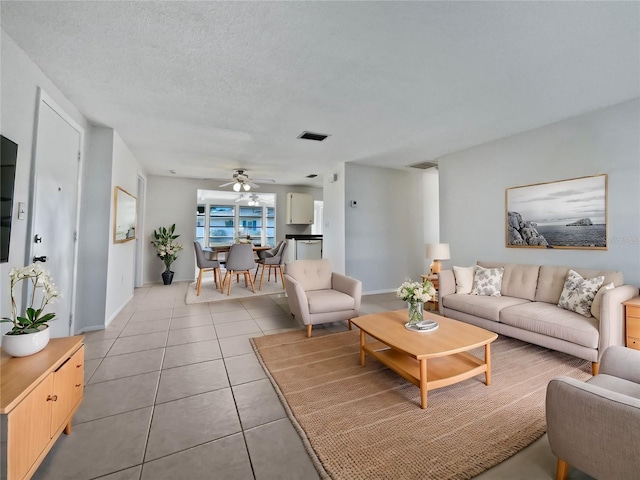 living room with ceiling fan, tile patterned floors, and a textured ceiling