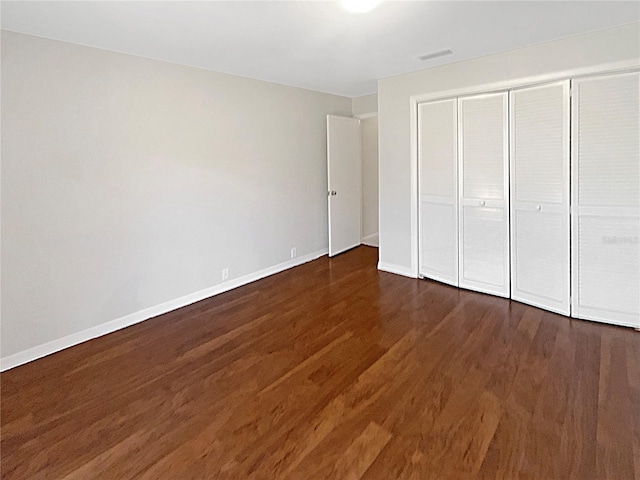 unfurnished bedroom featuring dark wood-type flooring and a closet