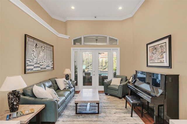 living room with recessed lighting, a high ceiling, wood finished floors, ornamental molding, and french doors