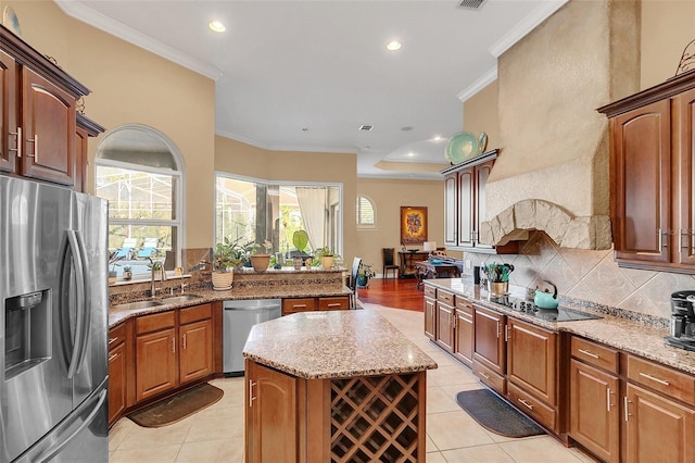 kitchen featuring a center island, crown molding, tasteful backsplash, appliances with stainless steel finishes, and a sink